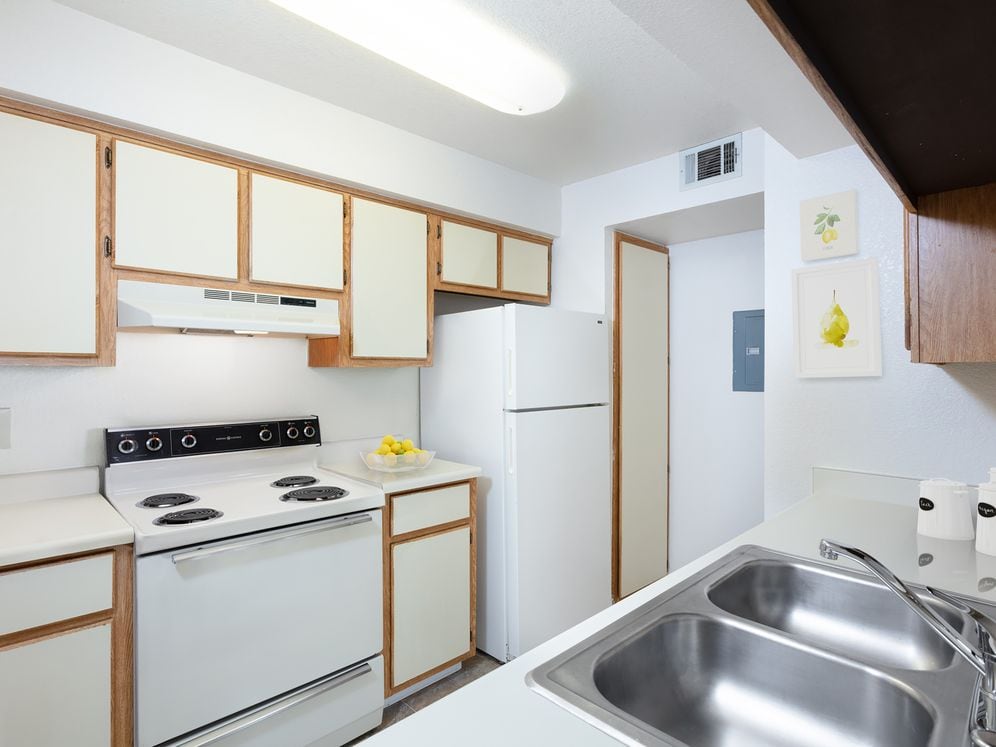 Traditional Collection kitchen with white appliances, beige and brown cabinetry, and laminate countertops