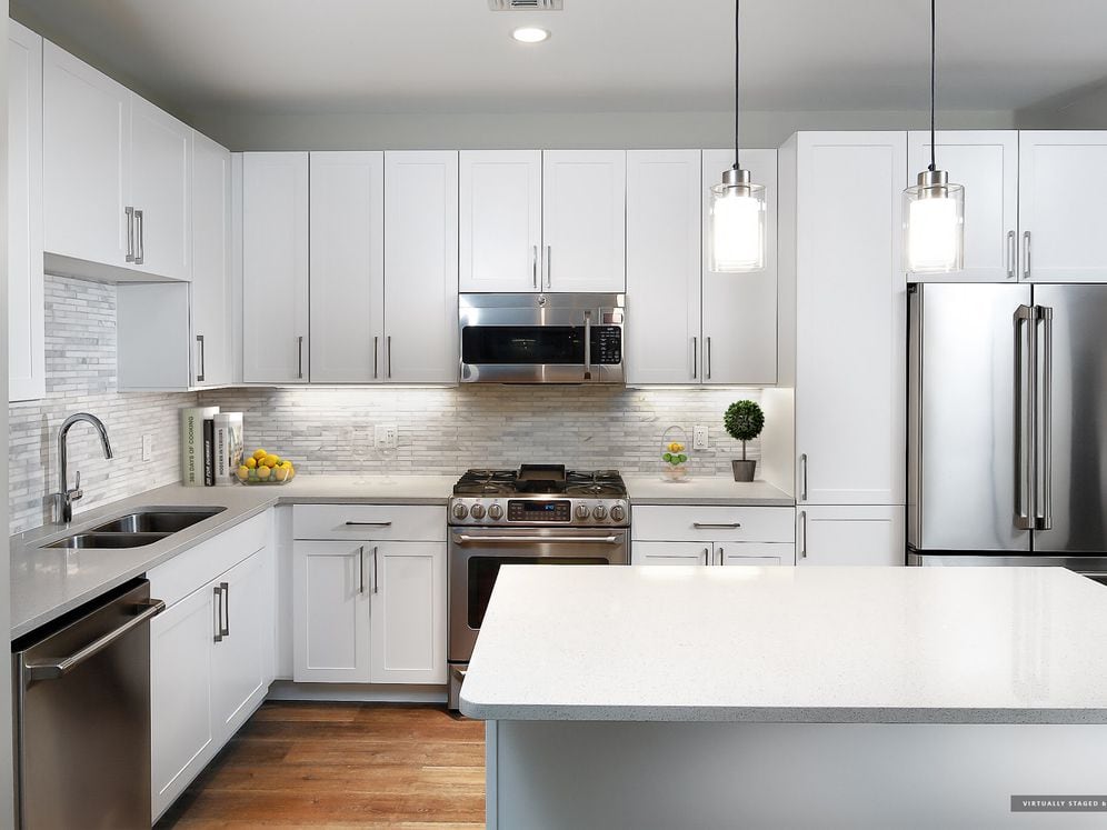 Signature Collection kitchen with white cabinetry, light grey quartz countertops, white marbled subway tile backsplash, stainless steel appliances, and hard surface flooring