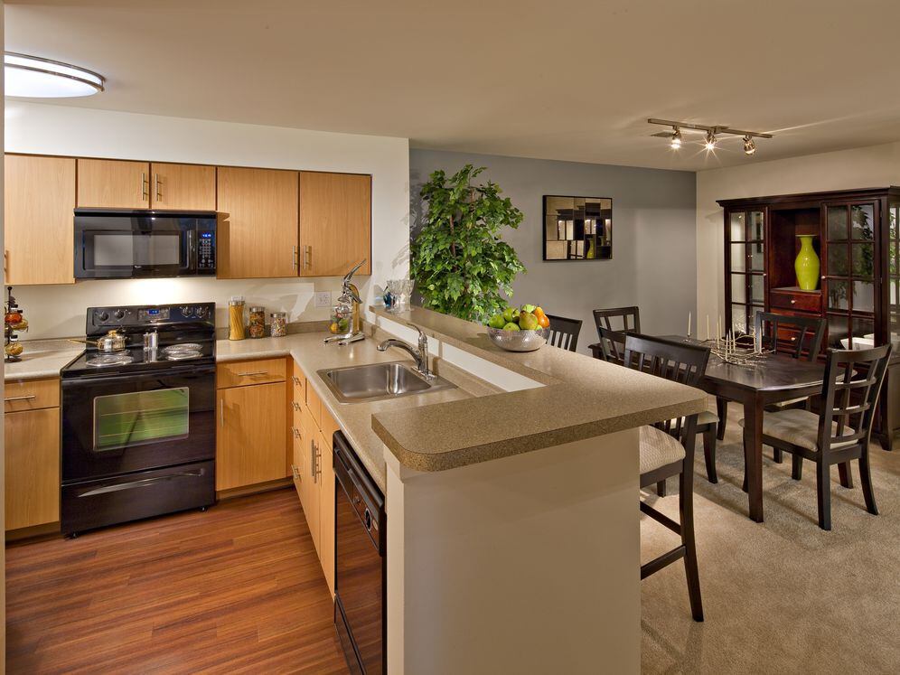 Classic Package kitchen with black appliances, grey laminate countertops, oak cabinetry, and hard surface flooring