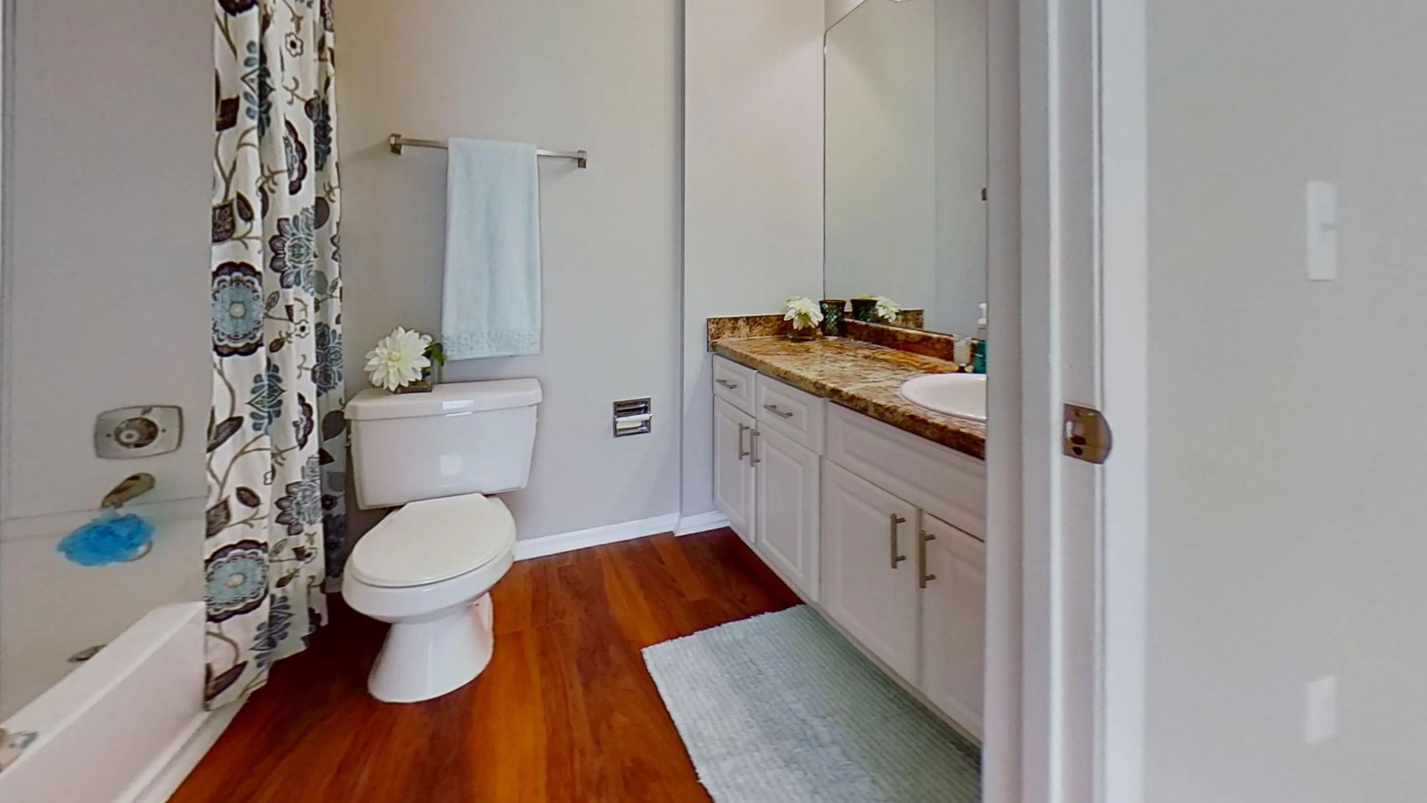 The Martinique Autograph floor plan offers a beautifully designed bathroom featuring a granite-style countertop, modern cabinetry, and hardwood-style flooring.