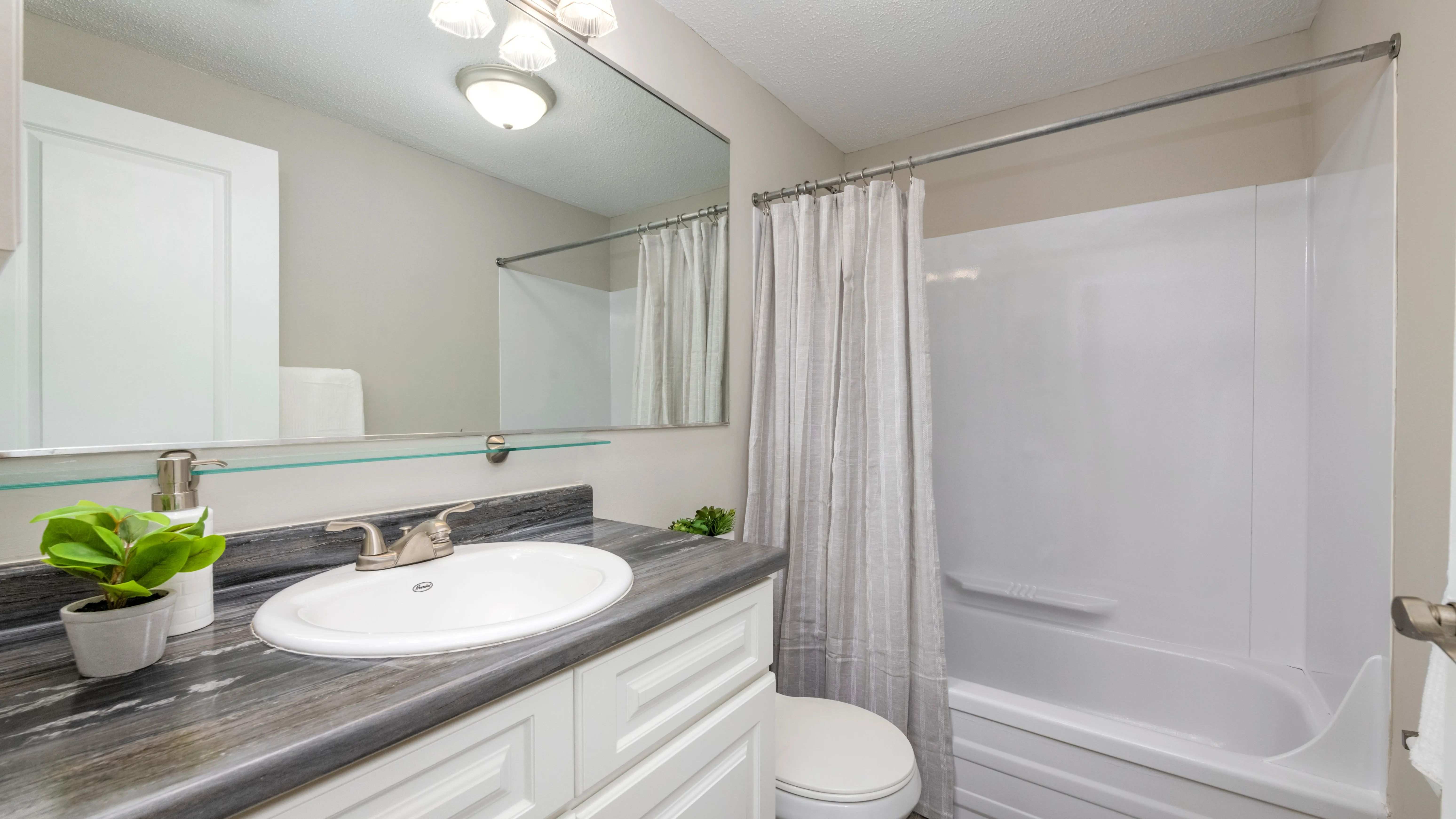 Experience timeless bathroom design with classic features including an oversized mirror and ample vanity lighting.