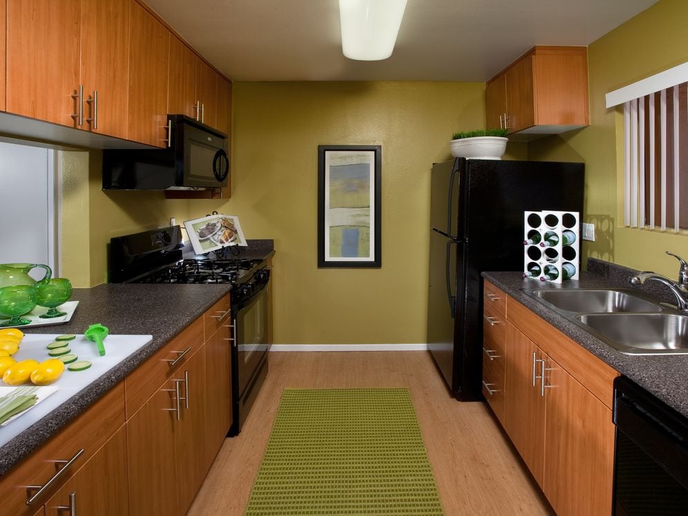 Classic Package kitchen with black appliances, grey speckled laminate countertops, oak cabinetry, and hard surface flooring