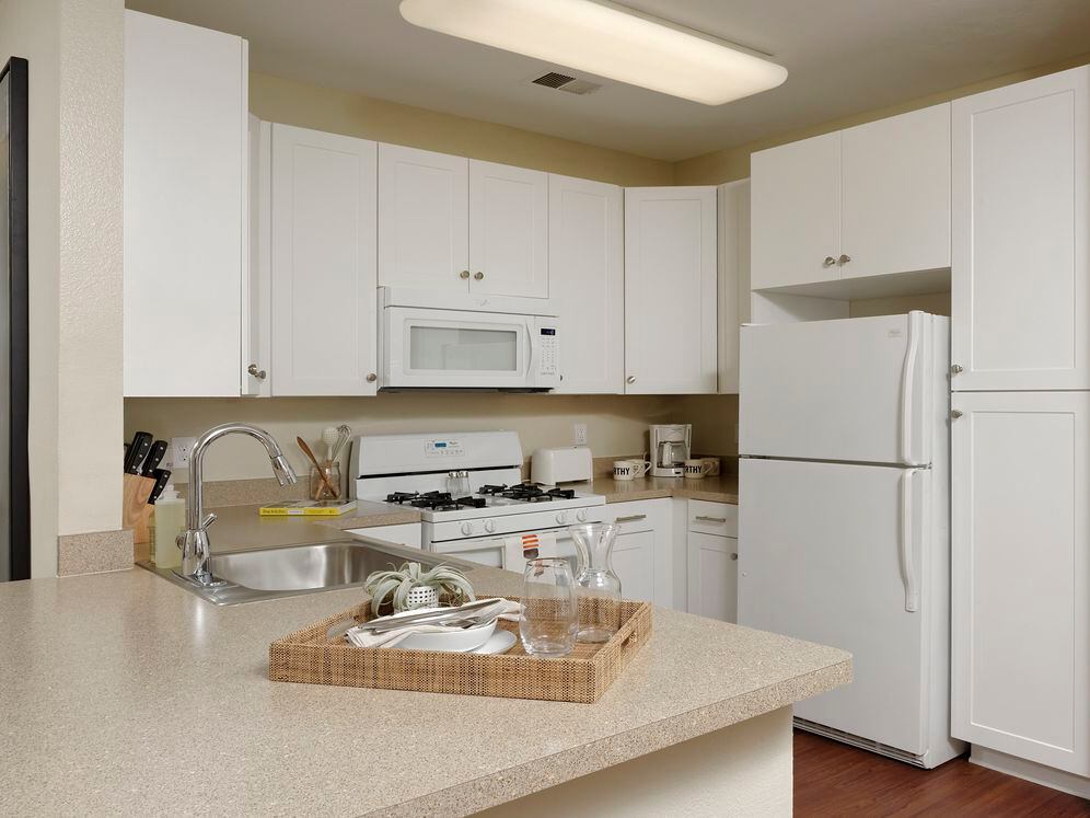 Classic Finish Package kitchen with which cabinetry, white appliances, formica countertops and hard surface flooring