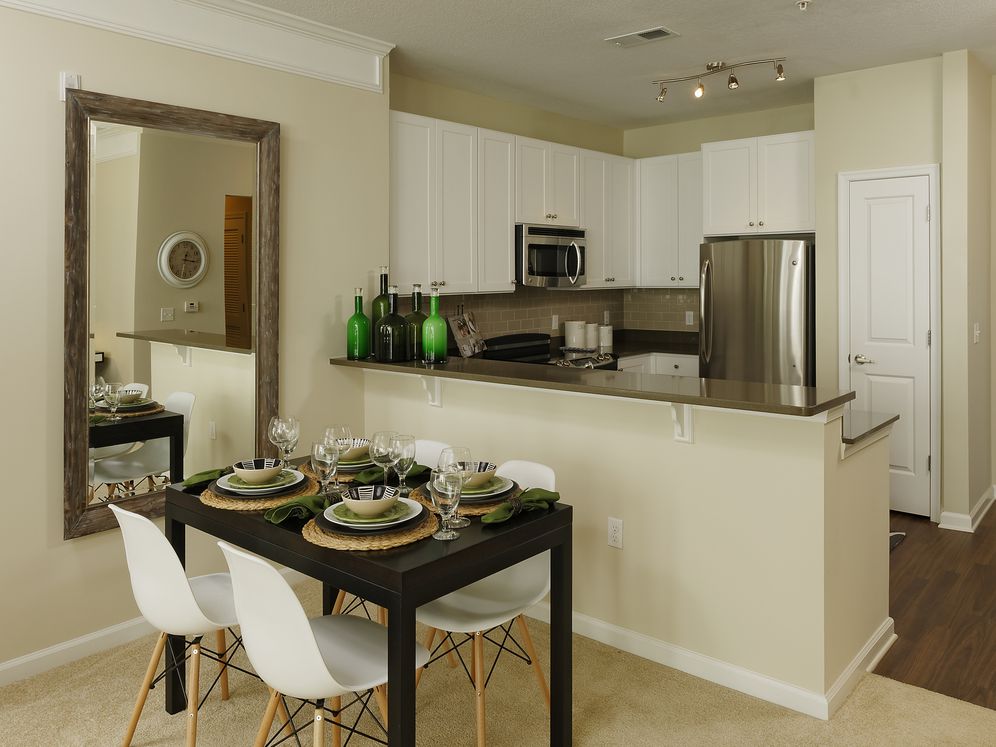 Dining area and kitchen with quartz stone countertop, white cabinetry, tile backsplash, stainless steel appliances and hard surface flooring
