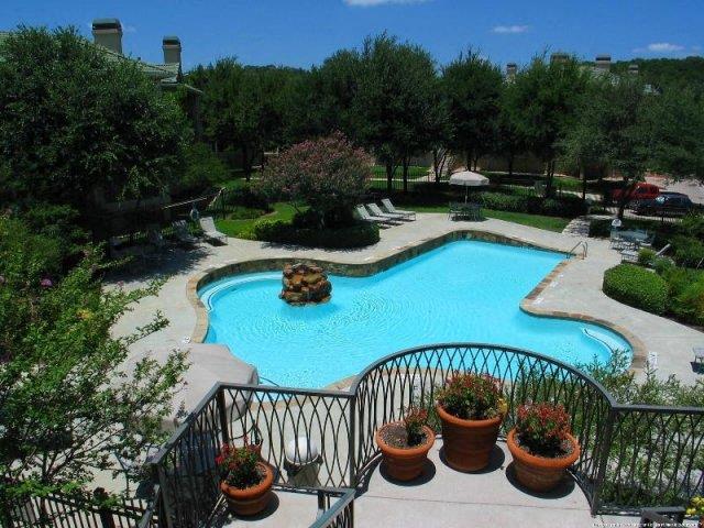 Terrace overlooking the pool surrounded by large trees and green space