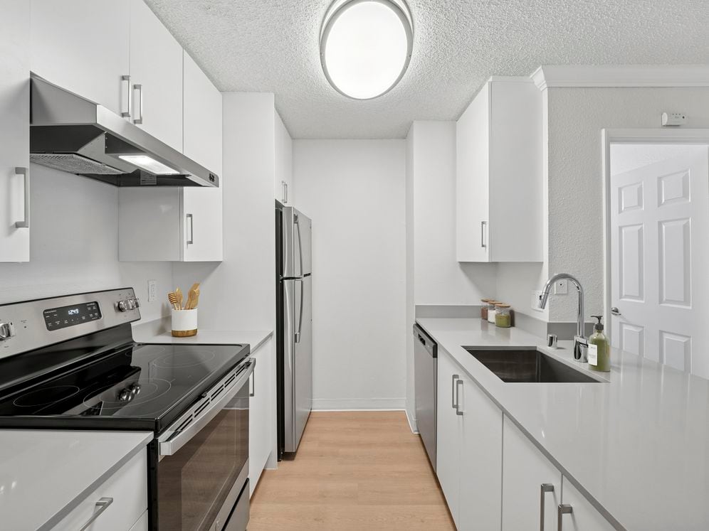 Renovated Package I kitchen with white cabinetry, grey quartz countertops, and hard surface flooring