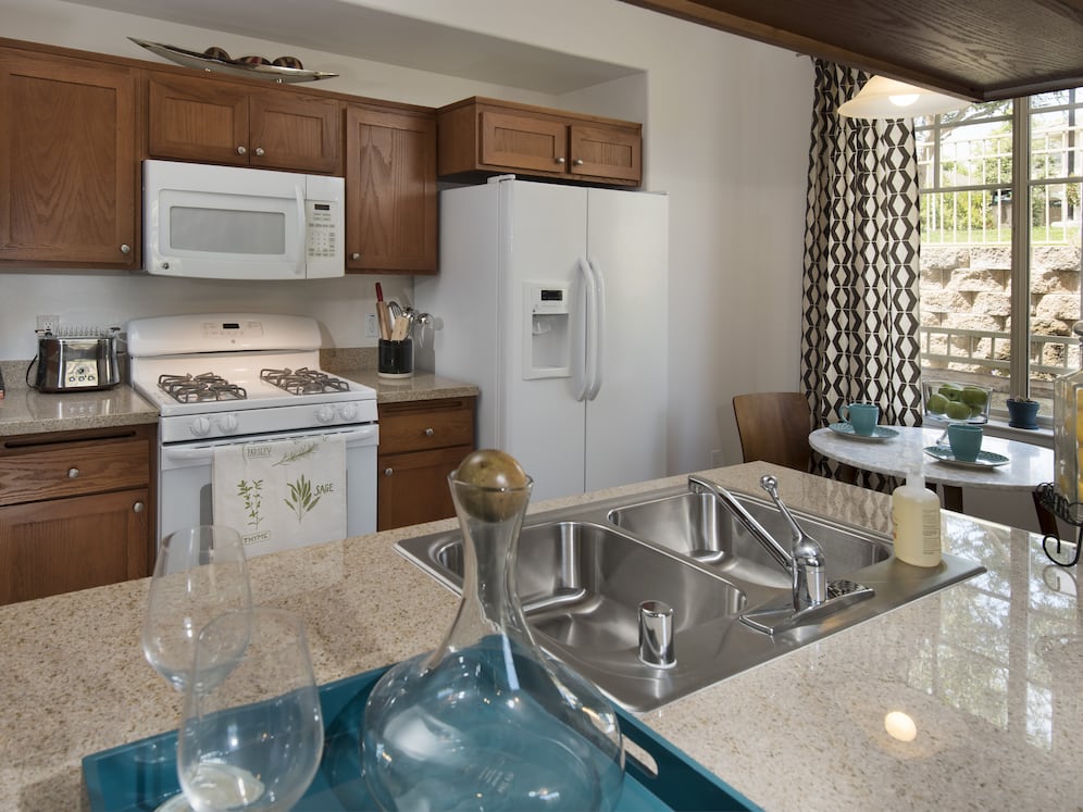 Classic Package I kitchen with maple cabinetry, beige speckled granite countertops, white appliances, and tile flooring