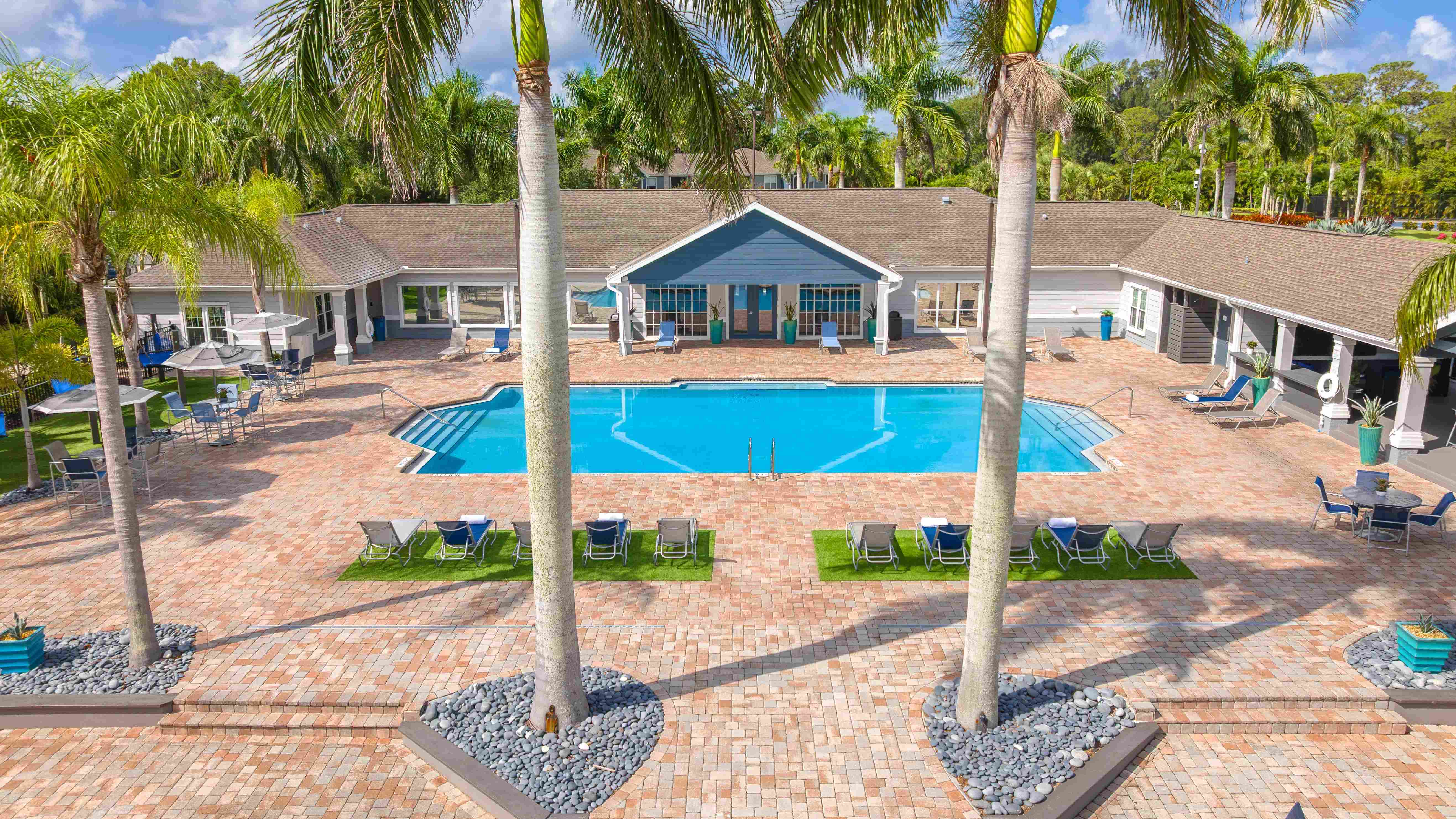 Aerial photo of resort-style pool with palm trees and lounge seating at Grand Oaks Apartments.