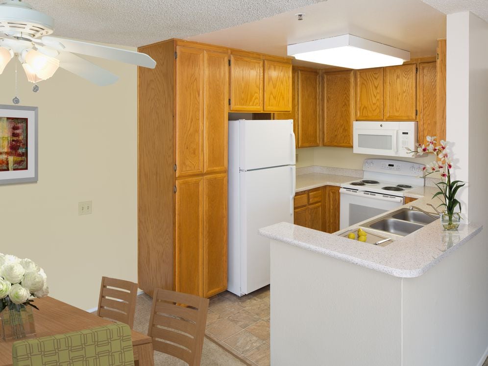 Classic Package kitchen with oak cabinetry, beige speckled laminate countertops, tile flooring, and white appliances