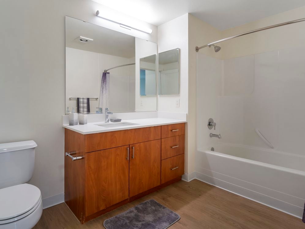 Newly renovated Finish Package II bath with white quartz countertops, cherry cabinetry, and hard surface flooring