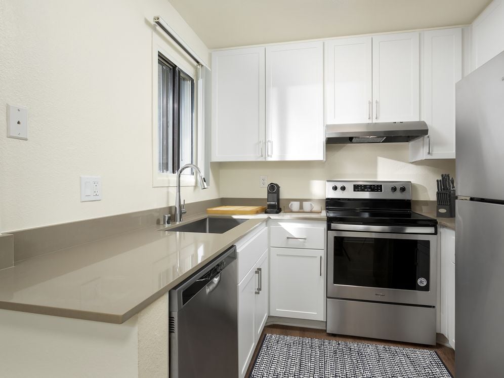 Renovated I kitchen with grey quartz countertops, white cabinetry, stainless steel appliances, and hard surface flooring