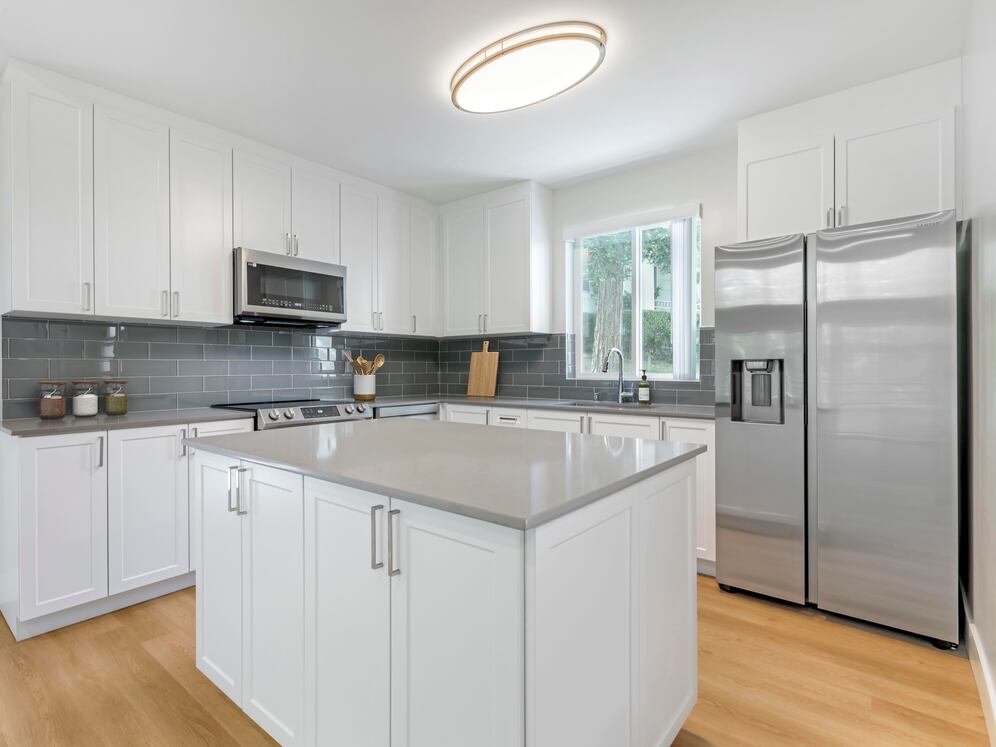 Freestanding Home kitchen with white cabinetry, grey quartz countertops, grey subway tile backsplash, stainless steel appliances, and hard surface flooring