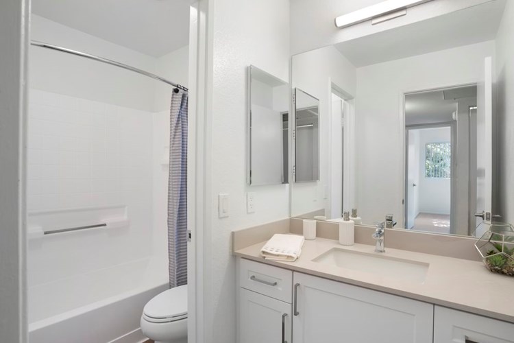 Renovated Package I bath with light grey quartz countertops, white cabinetry, and hard surface flooring