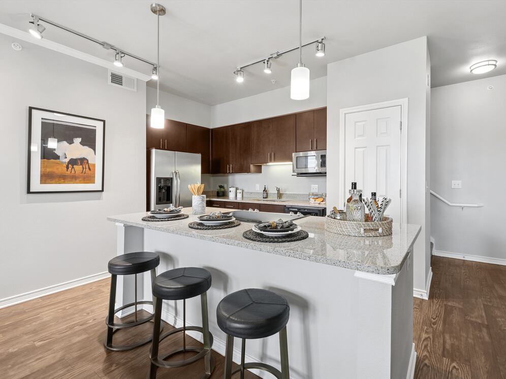 Kitchen with dark cabinetry, beige speckled granite countertops, stainless steel appliances, and hard surface flooring