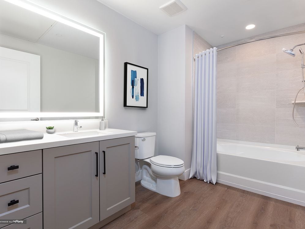 Signature Collection bath with grey cabinetry, white marble countertop, backlit mirror, and hard surface flooring