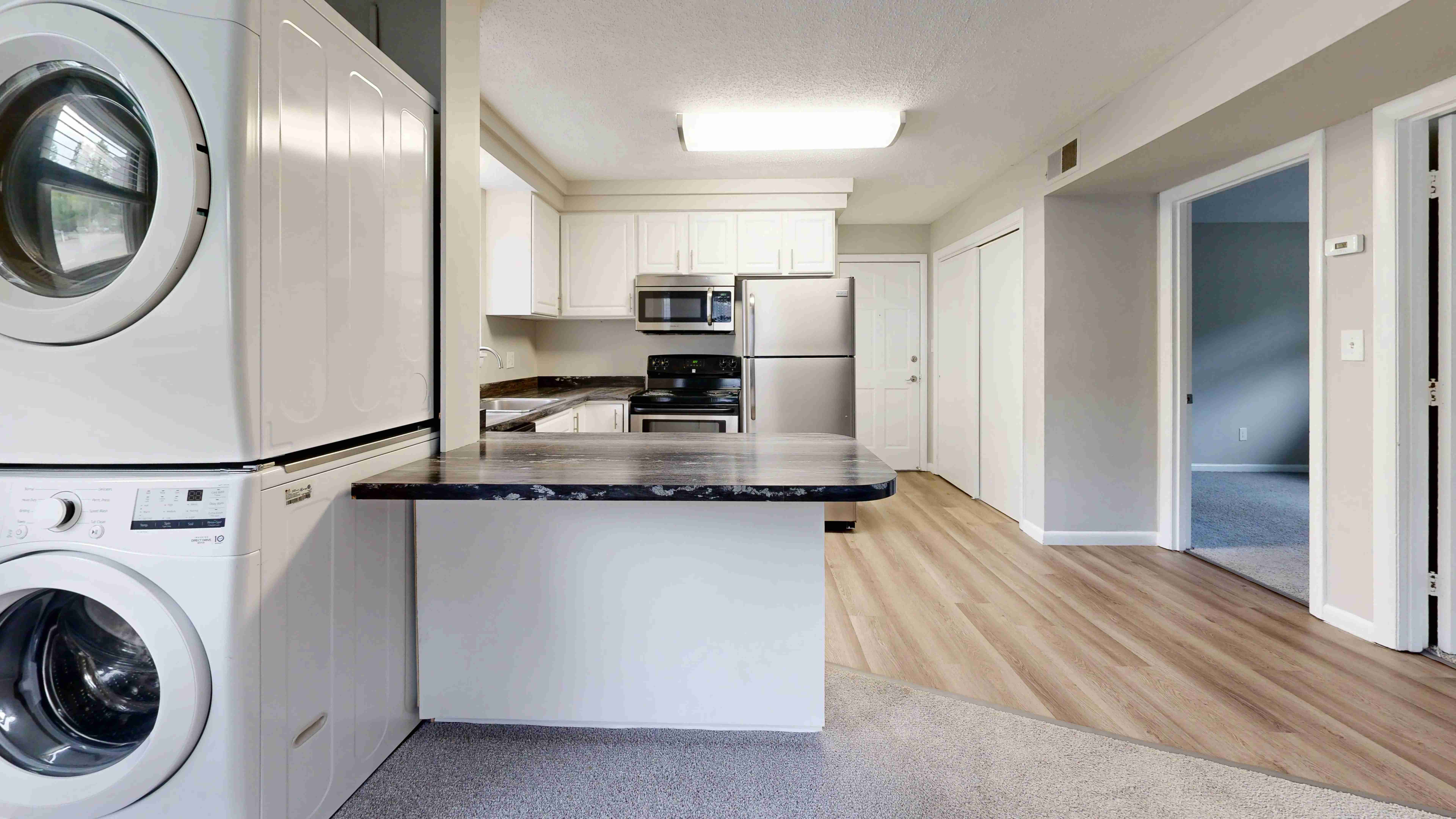 The Valley floor plan offers a kitchen with modern appliances, including a washer and dryer, stainless steel refrigerator, oven, and microwave, complemented by stylish countertops and cabinetry.
