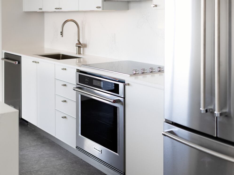 Signature Collection kitchen with white cabinetry, white marbled quartz countertop and backsplash, wine fridge, and upgraded stainless steel appliances