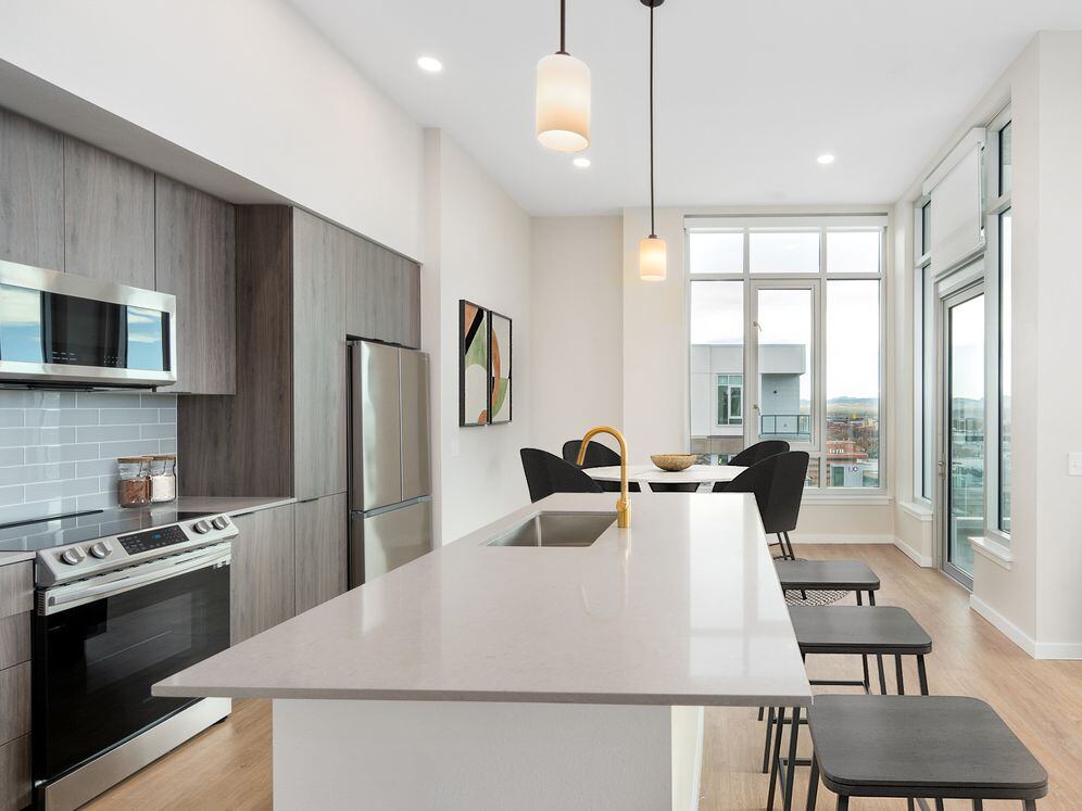 Signature Collection Kitchen with dark cabinetry, marbled quartz countertops and backsplash, upgraded stainless steel appliances, pendant lighting.