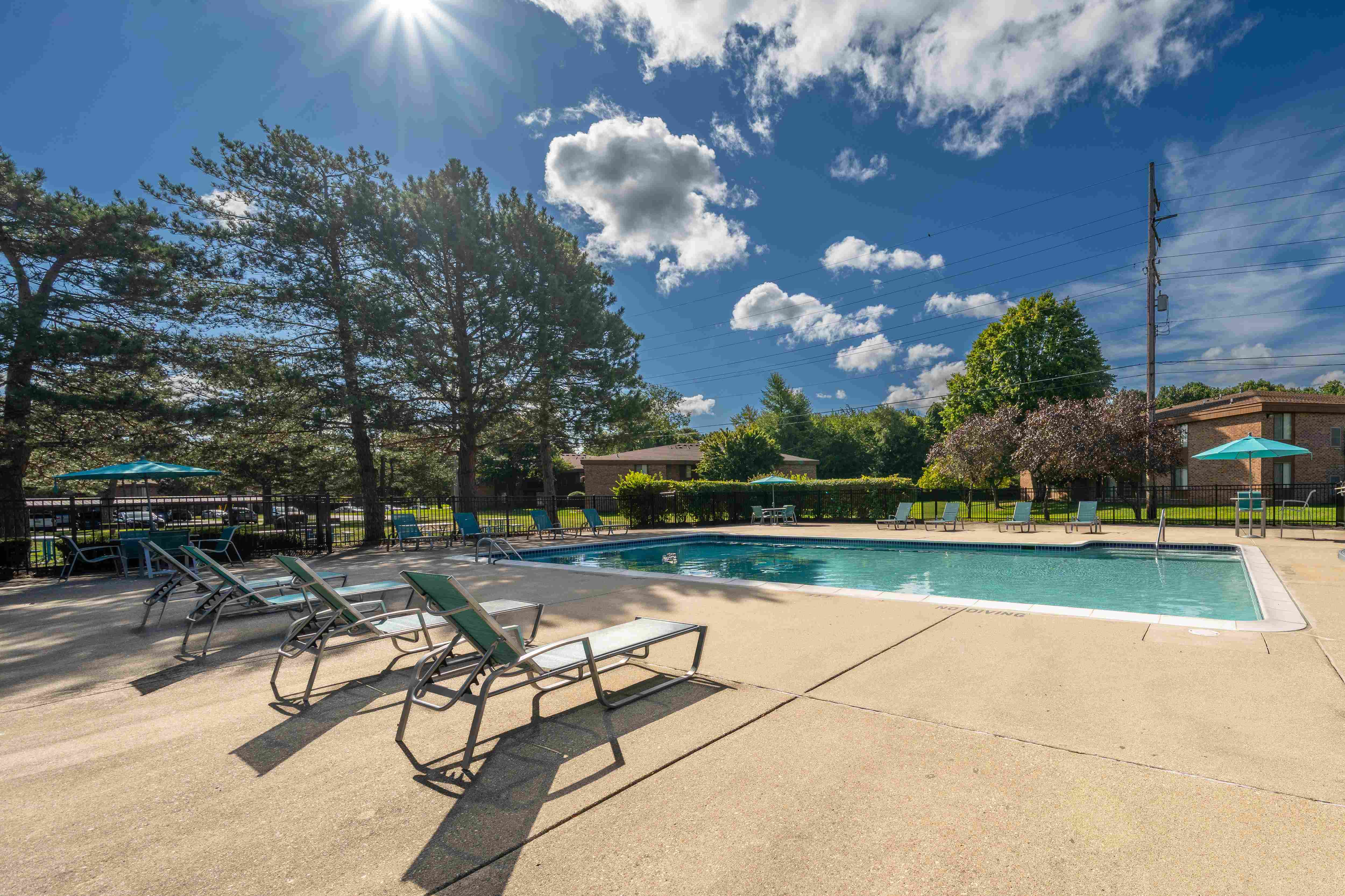 Heated pool equipped with comfy lounge chairs at Westwood Village Apartments in Westland, MI