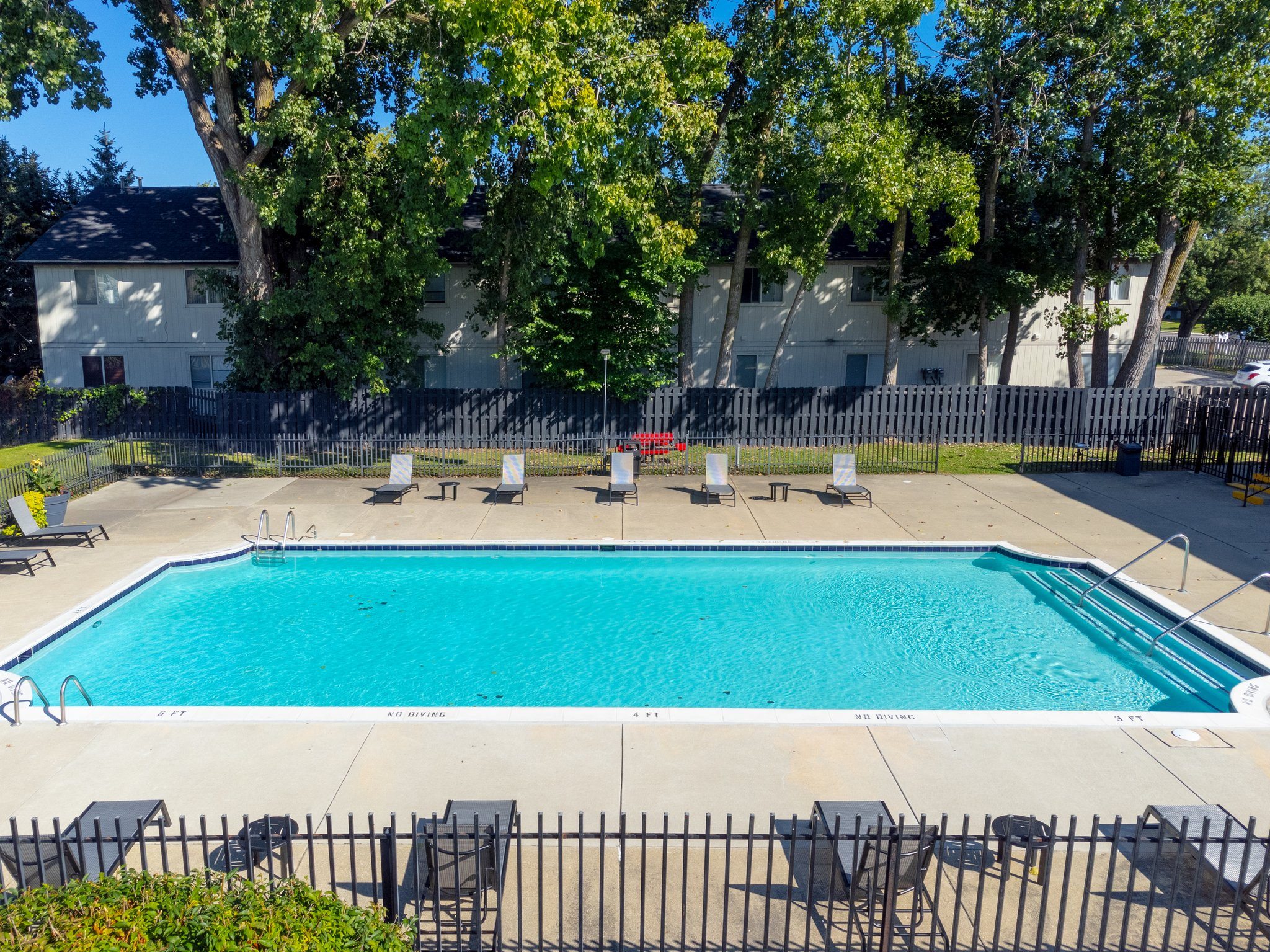 Heated Pool patio with lounge chairs at Knottingham Apartments in Clinton Township, MI