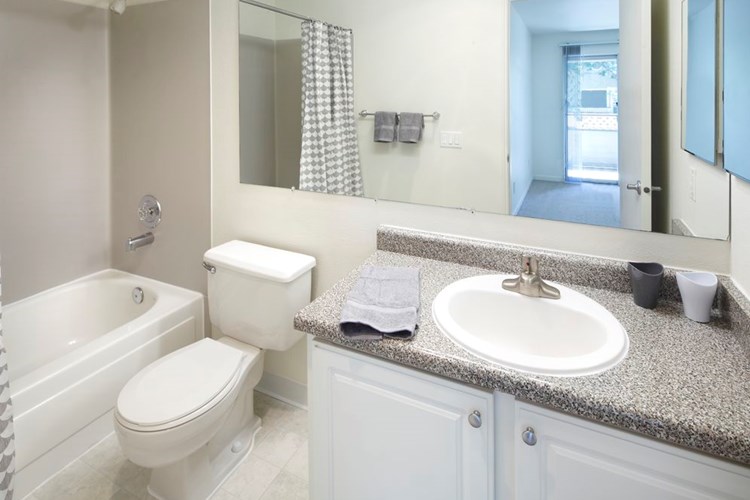 Renovated I bathroom with white cabinetry, grey speckled faux granite countertops, and hard surface flooring