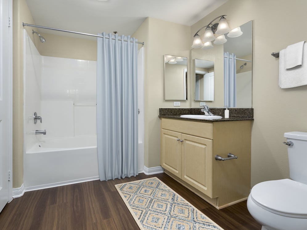 Classic Package I bath with brown speckled granite countertops, oak cabinetry, and hard surface flooring