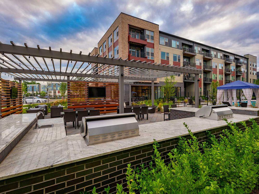 East building courtyard with barbecue grills, dining area, flat screen television, and lounge seating