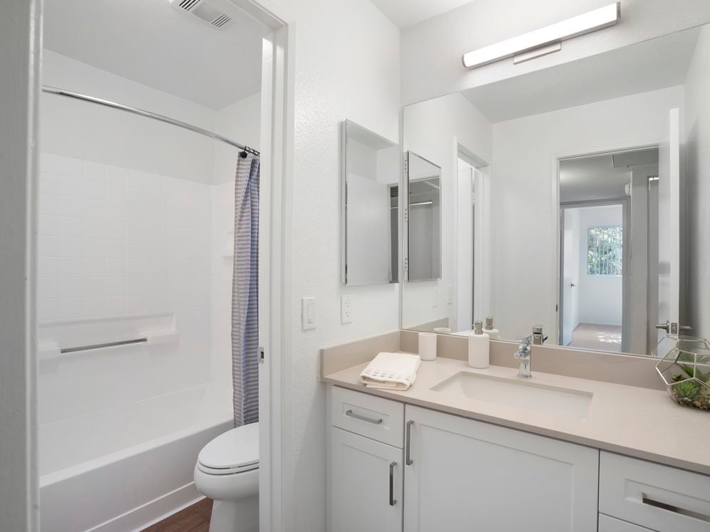 Renovated Package I bath with light grey quartz countertops, white cabinetry, and hard surface flooring