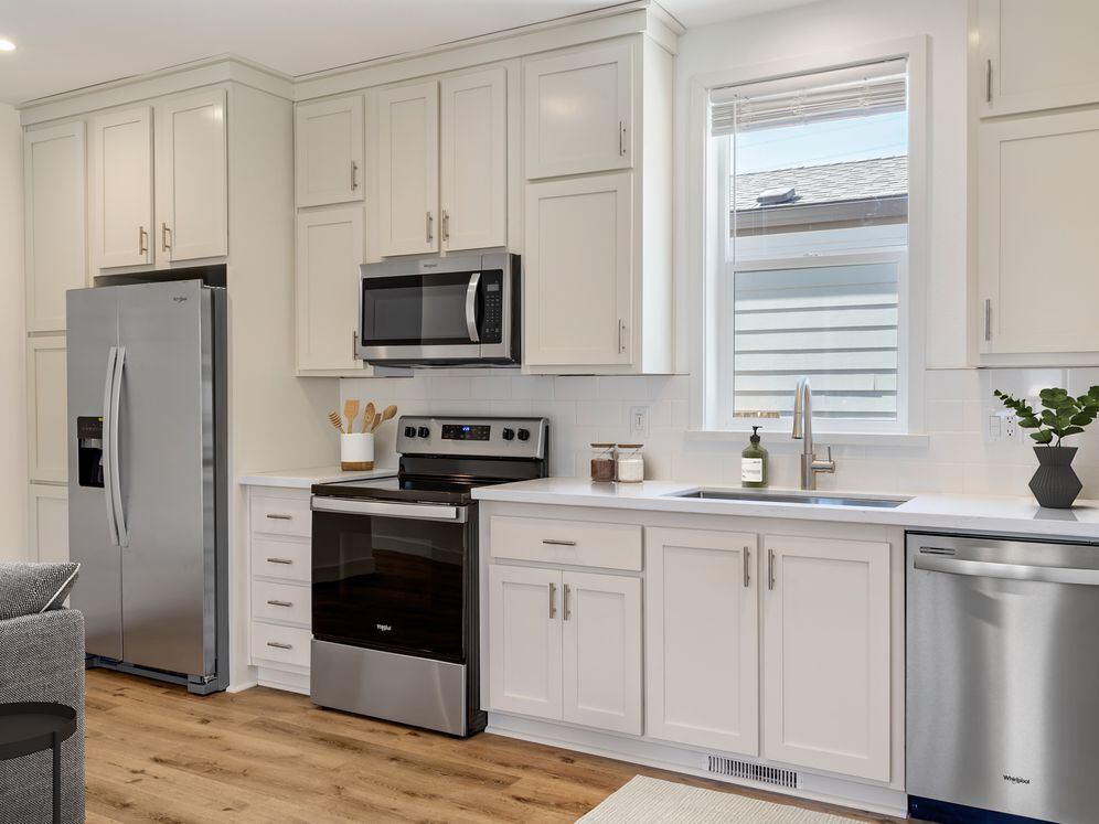 Freestanding Home kitchen with stainless steel appliances, white quartz countertops, white subway tile, white cabinetry, and hard surface flooring