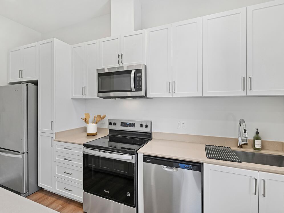 Freestanding Home kitchen with stainless steel appliances, white cabinetry, beige quartz countertops, and hard-surface flooring