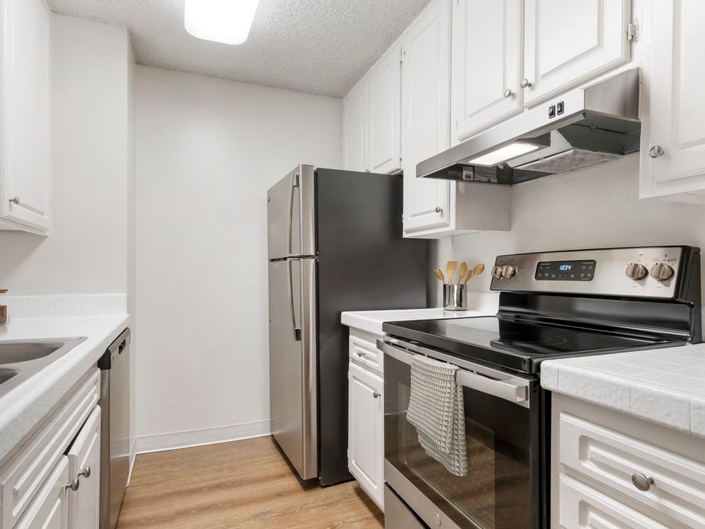 Classic Package II kitchen with stainless steel appliances, white tile countertops, white cabinetry, and hard surface flooring
