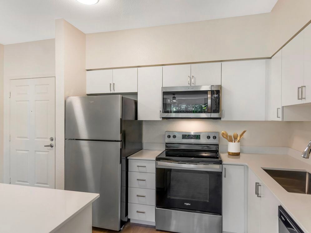 Renovated Package I kitchen with stainless steel appliances, white quartz countertops, white cabinetry, and hard surface flooring