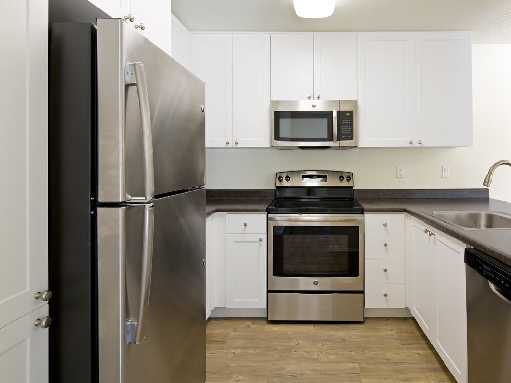 Renovated Package I kitchen with stainless steel appliances, white cabinetry, laminate countertops, and hard-surface flooring