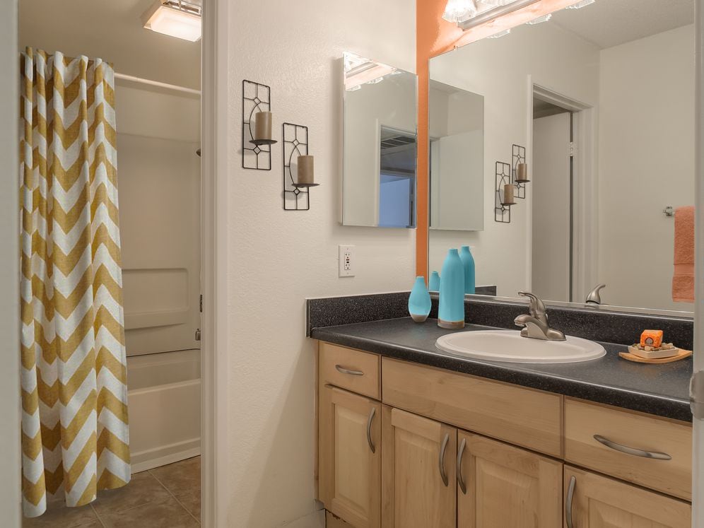 Baths with black laminate countertops and maple cabinetry