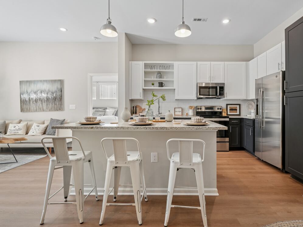 Kitchen with white and dark cabinetry, speckled granite countertops, white subway tile backsplash, stainless steel appliances, and hard surface flooring