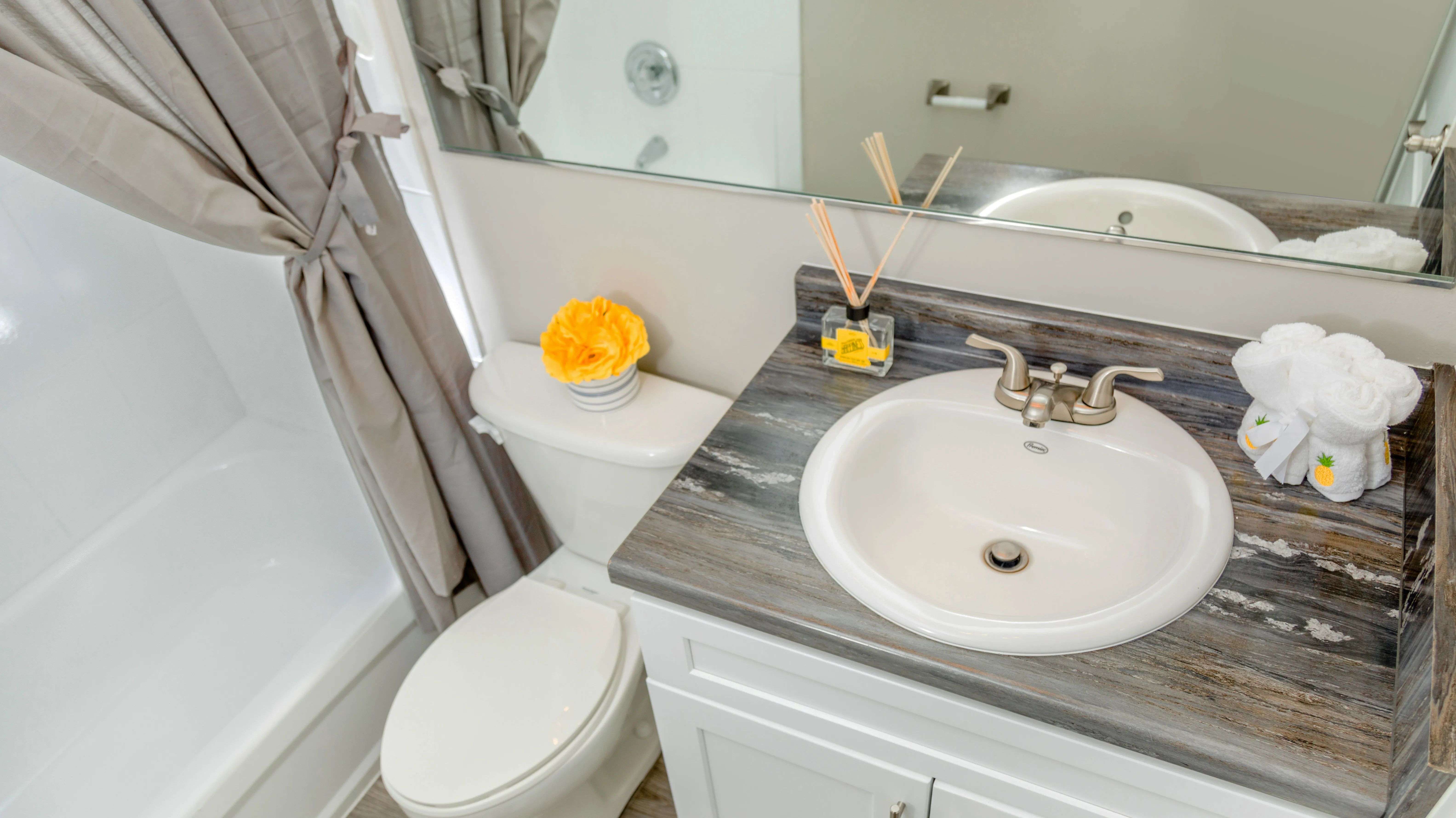 Newly remodeled bathrooms offering a refreshing escape with contemporary design - featuring black-fusion countertops, large mirrors, and wood-style flooring. 