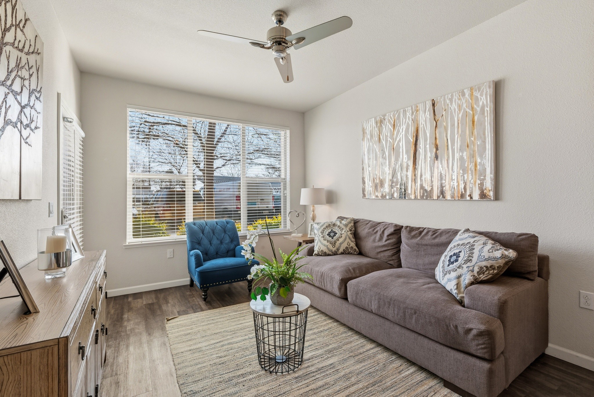 Aspire Apartments Tracy CA A living room with a blue chair and a painting of a tree on the wall.
