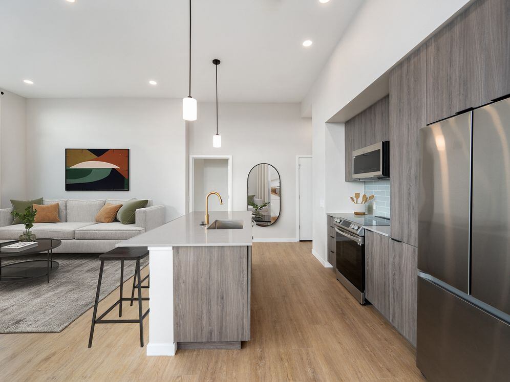 Signature Collection kitchen with dark cabinetry, marbled quartz countertops and backsplash, upgraded stainless steel appliances, and pendant lighting.