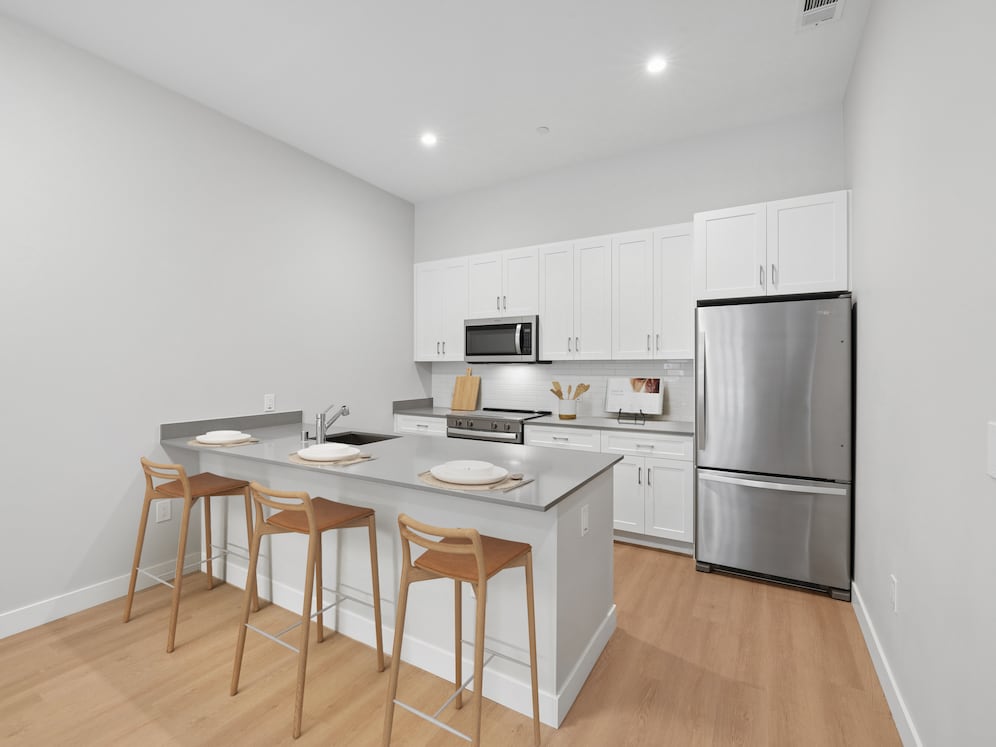 Upgrade Collection kitchen with stainless steel appliances, white cabinetry, grey quartz countertop, tile backsplash, and hard surface flooring