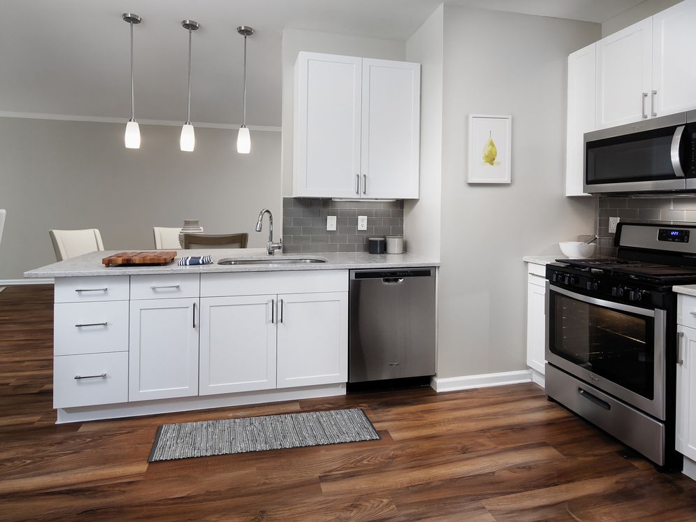 Classic Finish kitchen with white cabinetry, white quartz countertops, tile backsplash, stainless steel appliances, and hard surface flooring