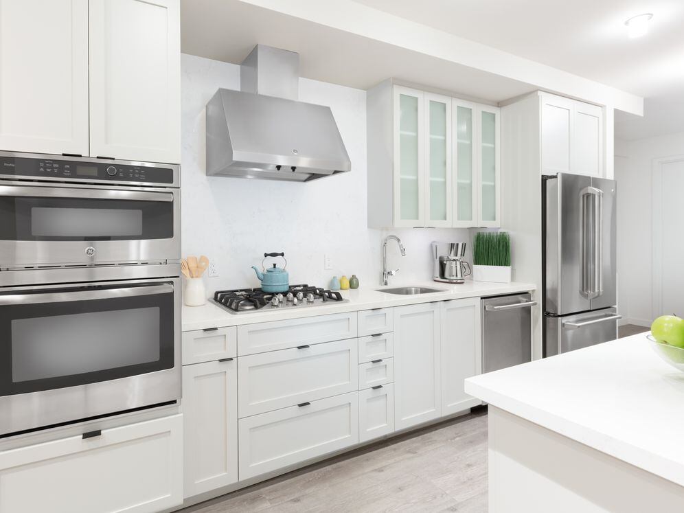Kitchen with white cabinetry, quartz stone countertops, ceramic tile backsplash and stainless steel appliances