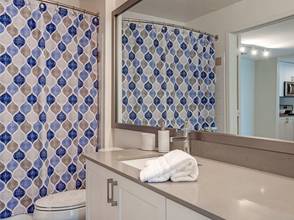 Renovated Package I bath with white cabinetry, quartz countertops, and hard surface flooring