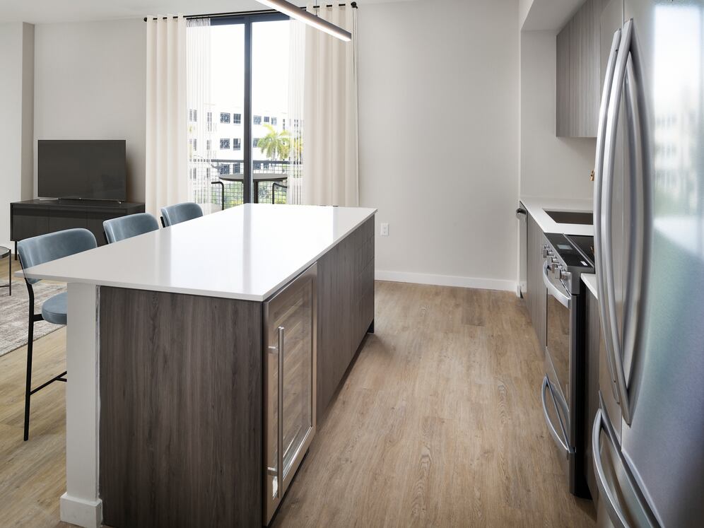 Upgrade Collection II Three-bedroom apartment kitchen with espresso cabinetry, white tile backsplash, white quartz countertop, and hard-surface vinyl plank flooring