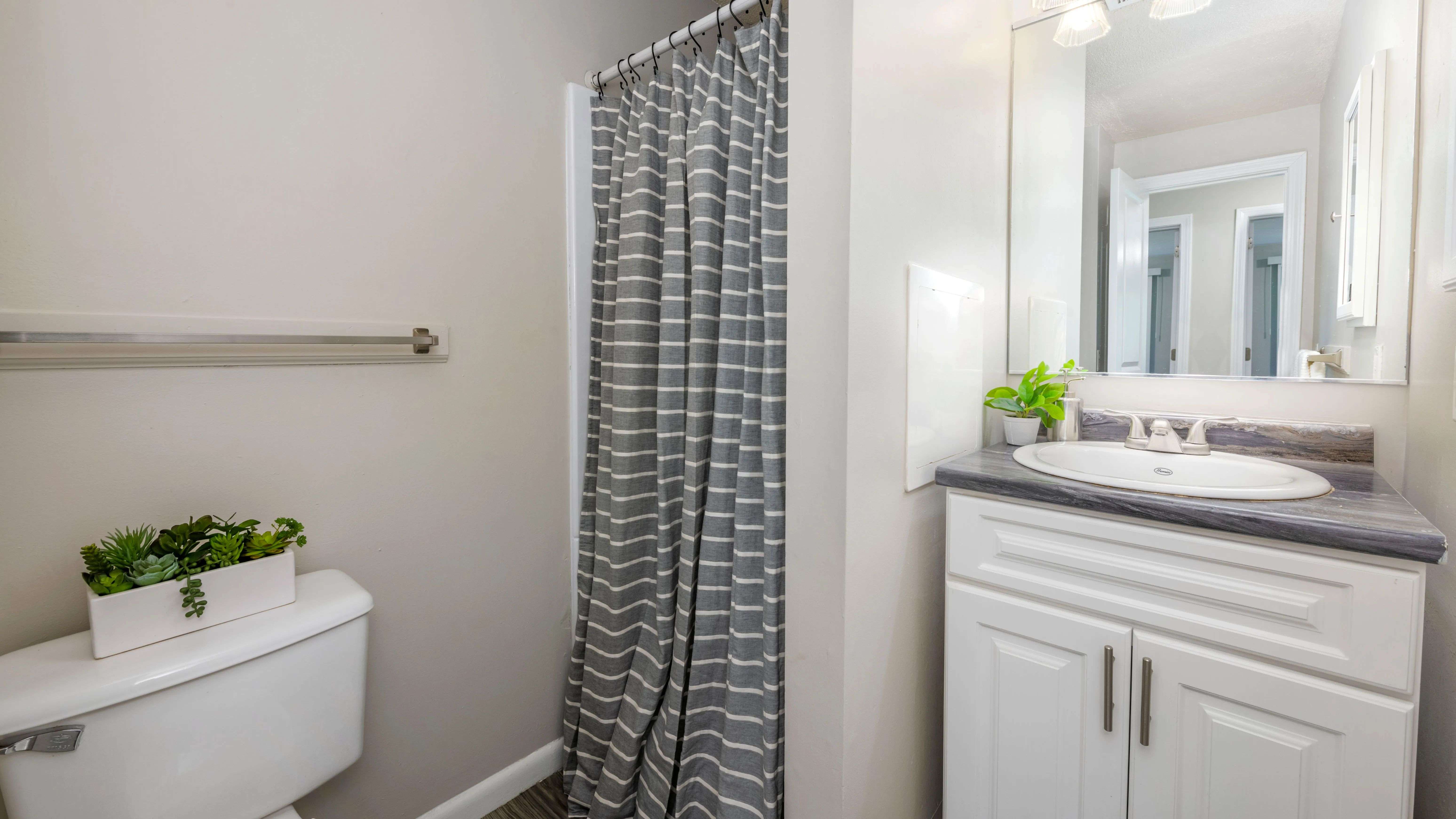 Our modern bathroom showcases black fusion granite-style countertops and a spacious walk-in shower. Your daily sanctuary awaits.