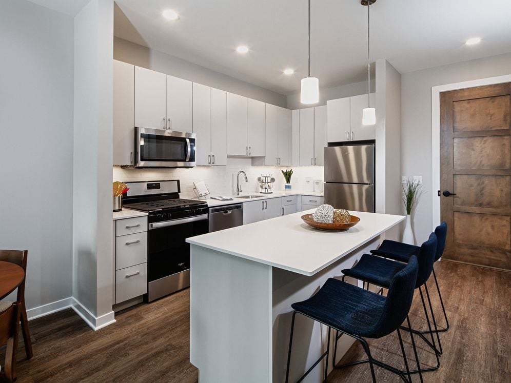 Base Scheme apartment home kitchen with light grey cabinetry, stainless steel appliances, and hard surface flooring