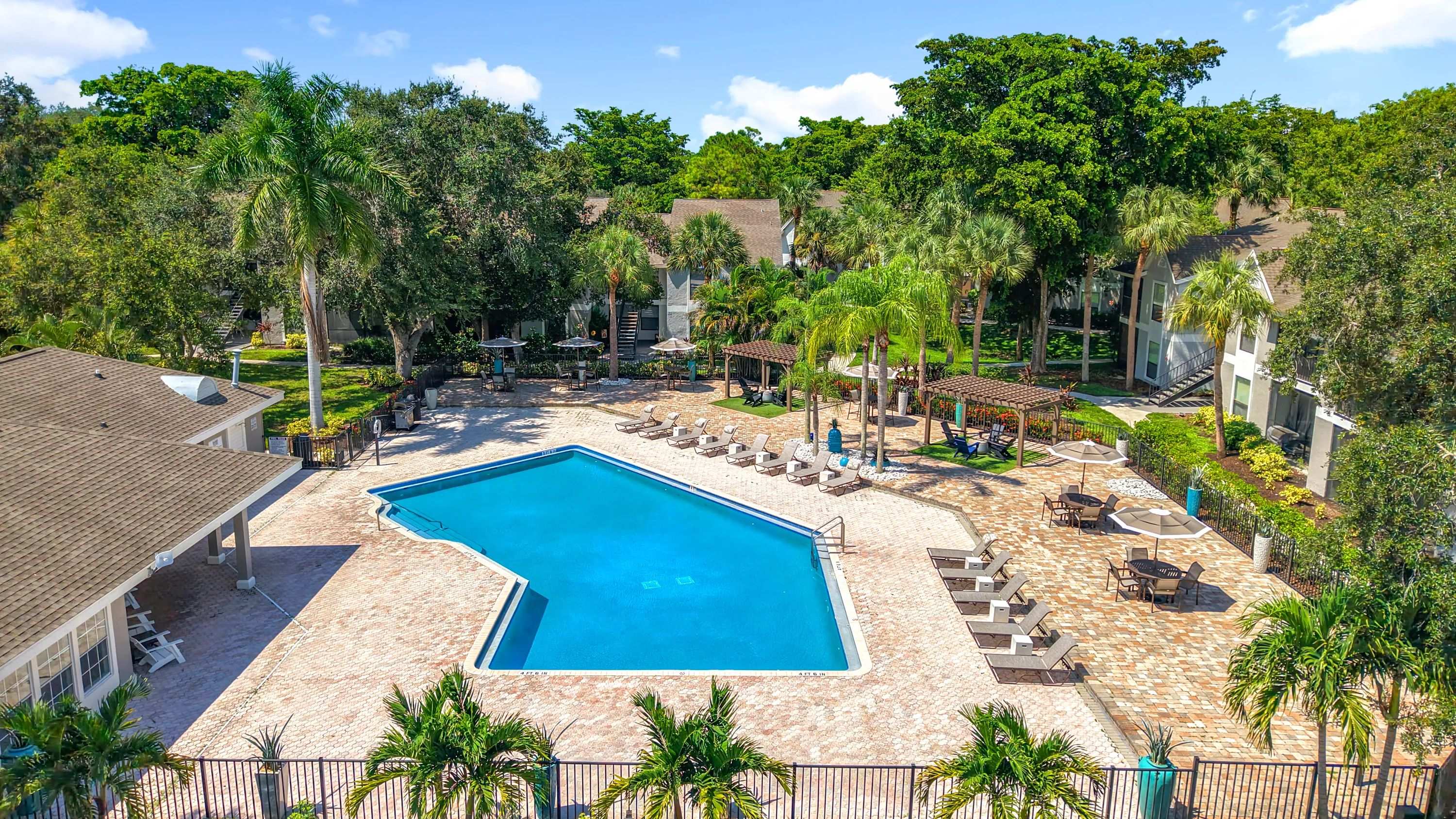 Lounge in style beneath swaying palms at our beautifully maintained pool area, complete with seating, umbrellas, and a peaceful tropical vibe.