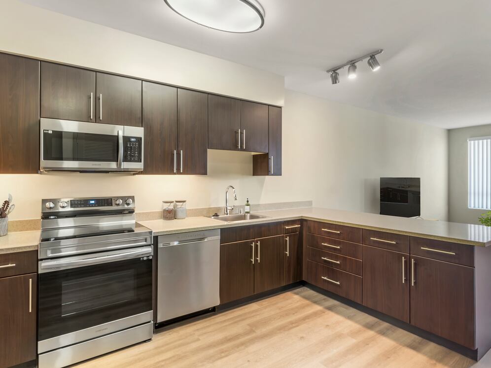 Renovated Package I kitchen with stainless steel appliances, grey speckled granite countertops, espresso cabinetry, and hard surface flooring