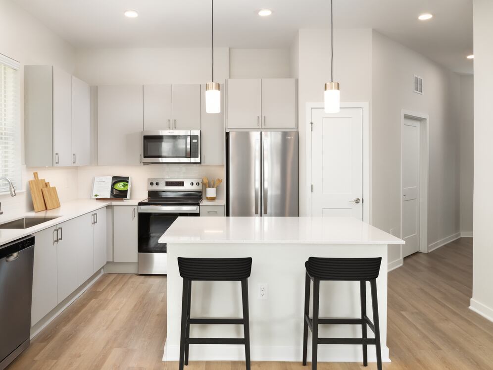 Base Collection kitchen with stainless steel appliances, white quartz countertops, white tile backsplash, grey cabinetry, and hard surface flooring