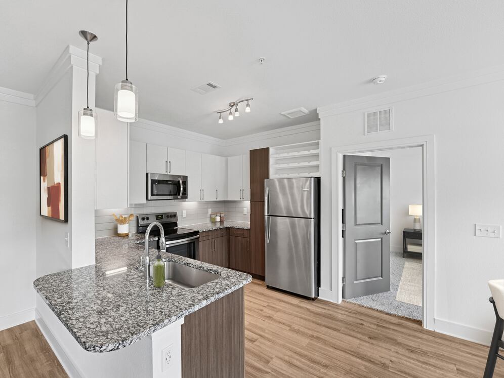 Kitchen with white and espresso cabinetry, speckled granite countertops, stainless steel appliances, and hard surface flooring