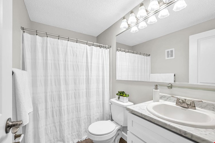 Newly remodeled bathrooms featuring wood-style flooring and marble-style counter tops.